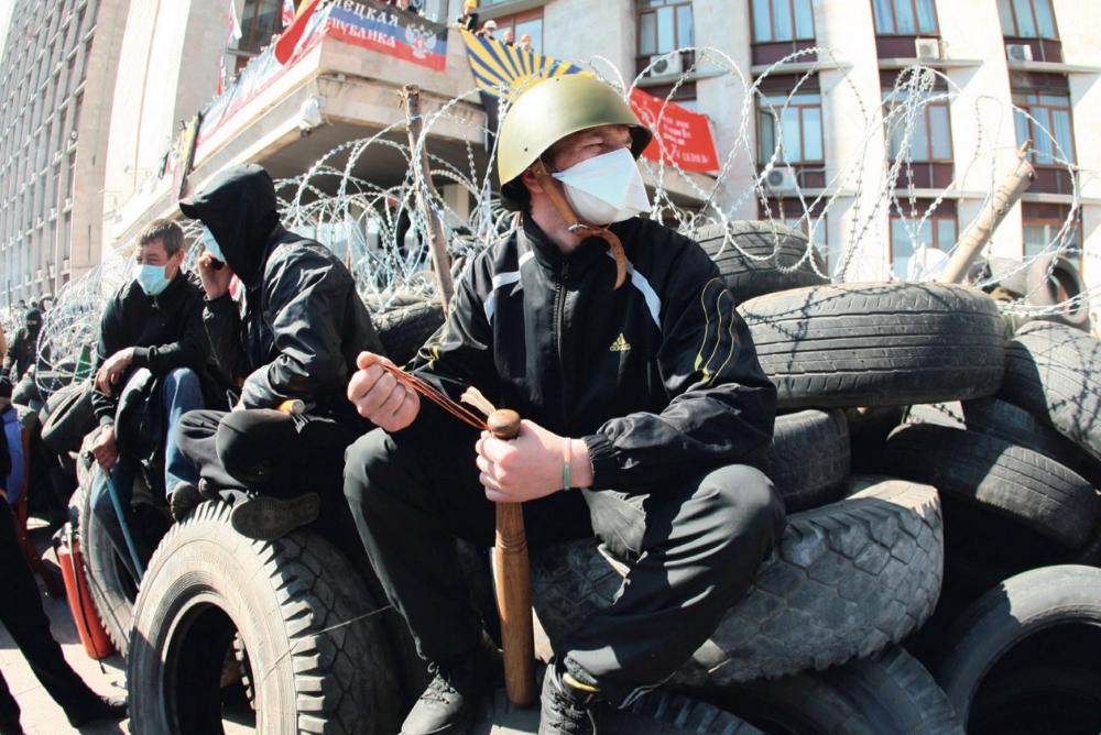 A pro-Russian Militant holding a bat guards a barricade in front of the Donetsk regional administration building on April 8th, 2014.  Photocredit: Alexander KHUDOTEPLY/AFP