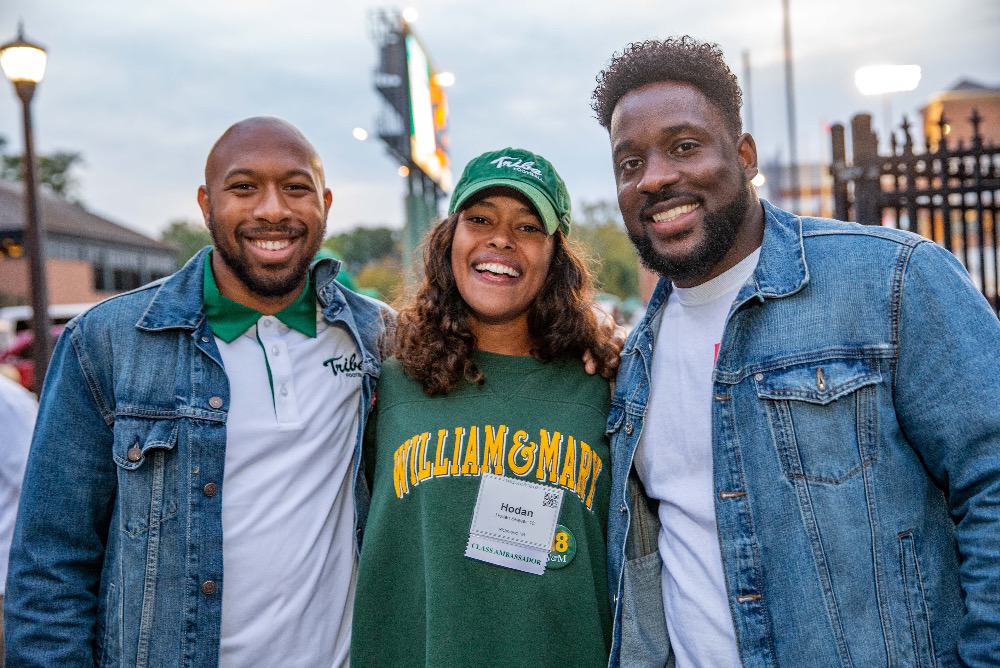 Three alumni standing together and smiling