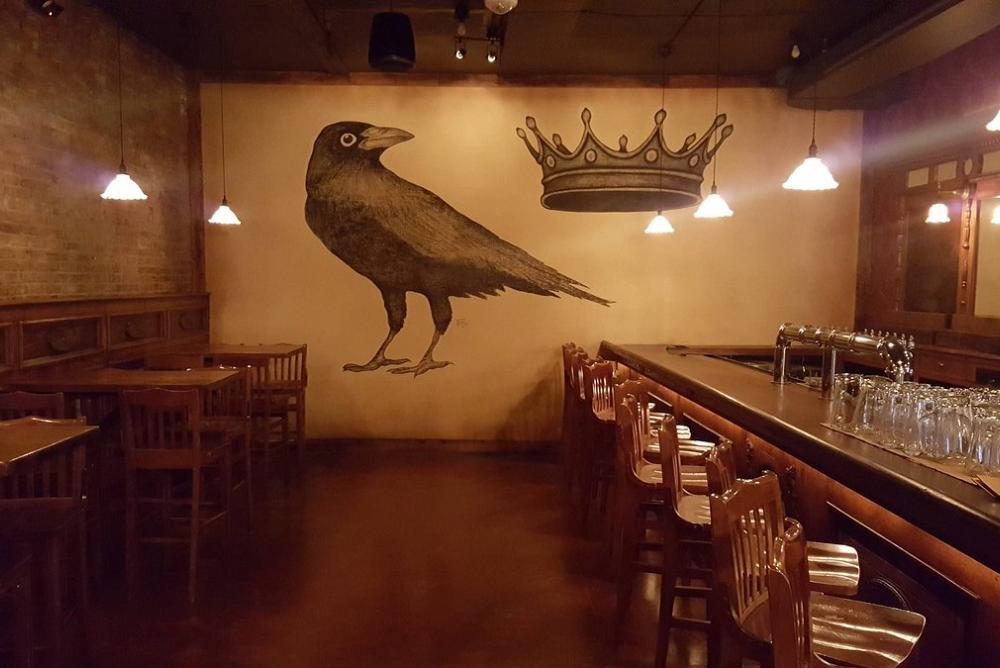 Pictured: The Crown & Crow venue. An empty bar with ambient lighting and a large image of a crow and a crown on the back wall