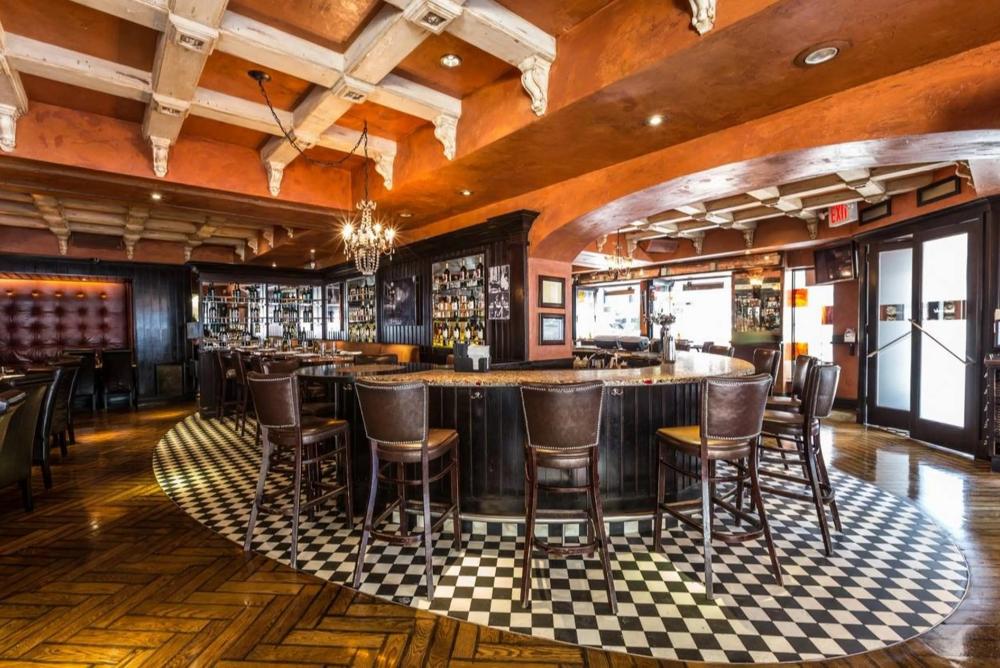 Pictured: Banc Cafe venue. Ambient lighting with tile flooring around the barstools and bar and wooden panel flooring outside the perimeter of the bar stools.