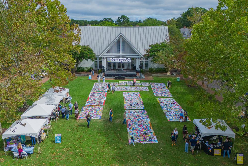 Bird's-eye view of the Community Art Day showing the Communal Quilt, student art vendor tents and attendees.