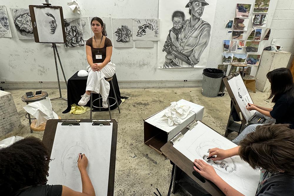 Classroom with students drawing a live model in charcoal