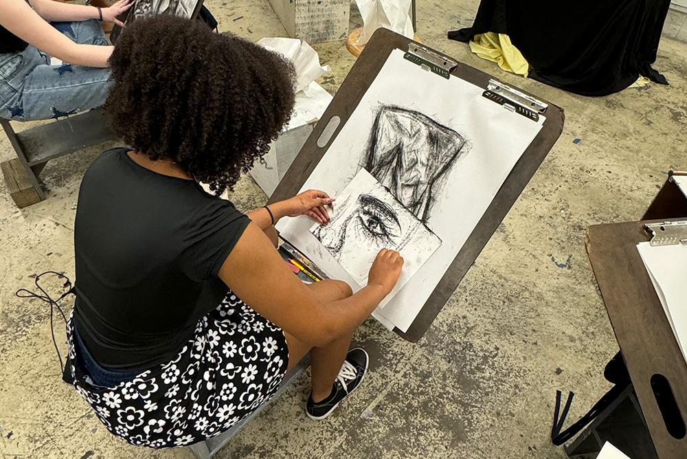 Student drawing a live model in charcoal