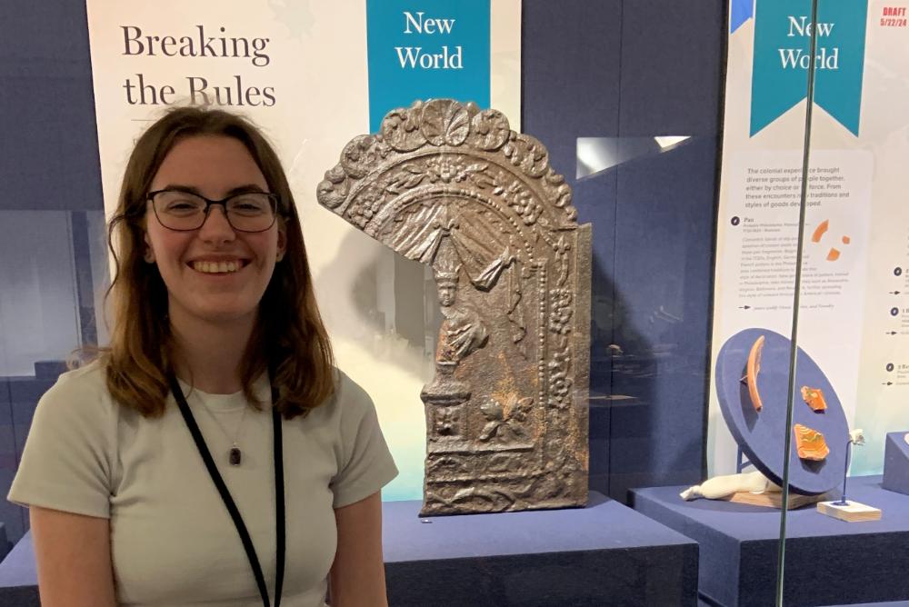 a woman standing in front of sculpture fragment as part of a display