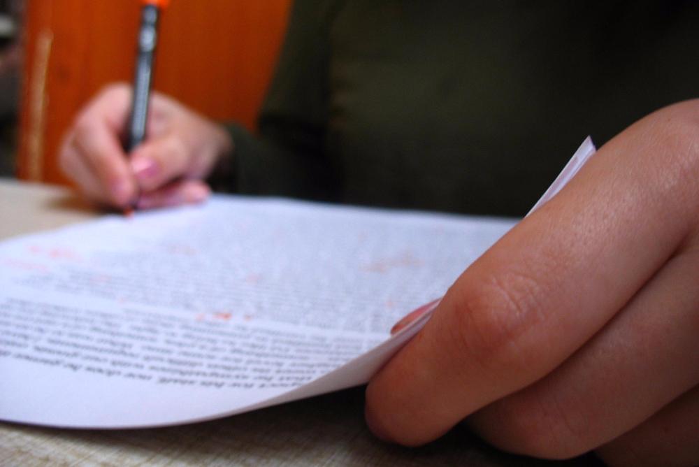 Hand holding a pen, marking a paper.