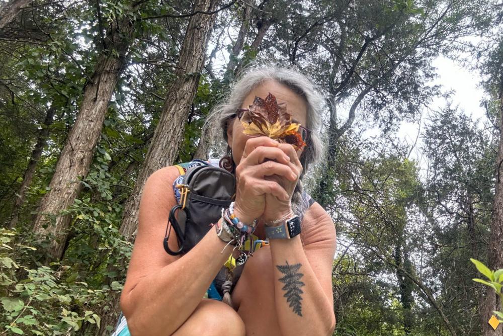 A woman holds a leaf infront of her face