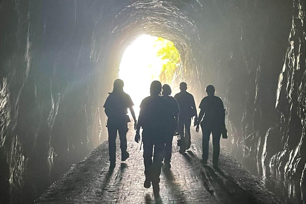five people walking out of a light at the end of a tunnel