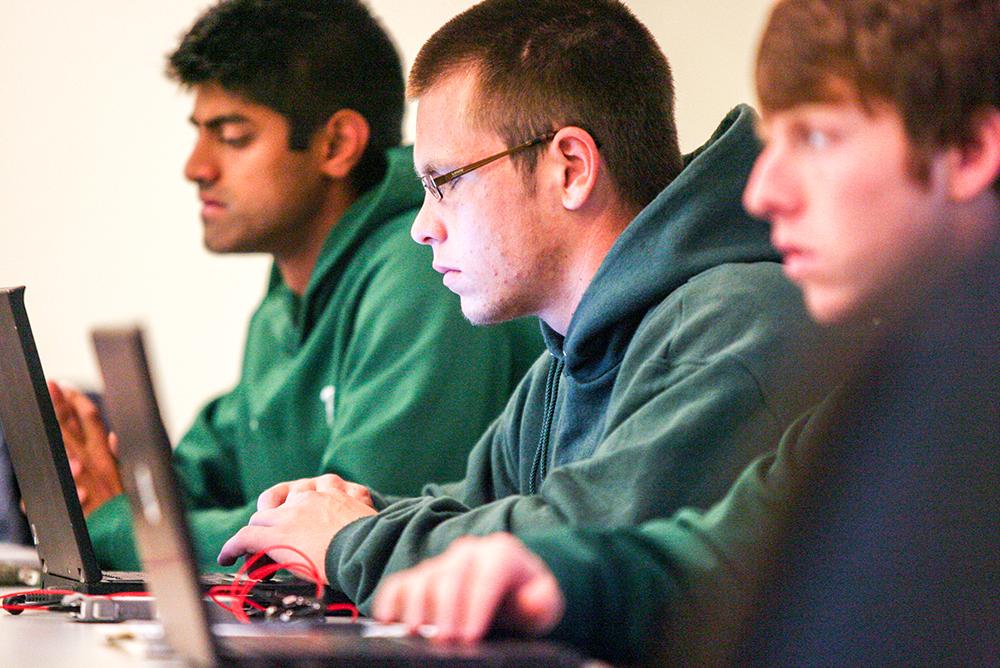 Three male students work on laptop computers.